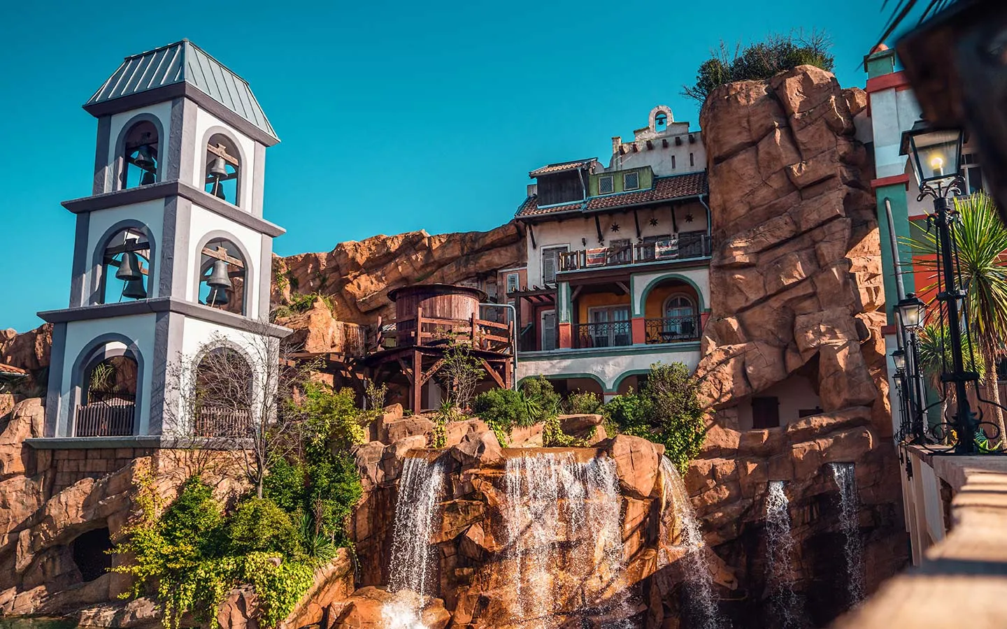 Vibrant Mexican-themed area at Phantasialand featuring colorful buildings with traditional architecture, decorative elements, and possibly water features set against rocky formations, showcasing the immersive themed environment described as the authors favorite area of the park